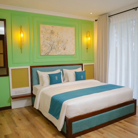 Ein stilvolles Hotelzimmer mit einem großen Bett, grünen Wänden und eleganten Beleuchtungselementen, die eine entspannende Atmosphäre schaffen.