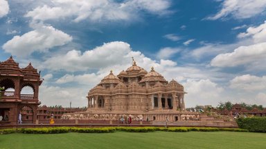Ein majestätischer Tempel mit historischen Statuen und aufwändigen Details, eingebettet in eine grüne Parklandschaft.