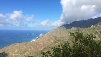 Eine atemberaubende Küstenlandschaft mit steilen Bergen und dem tiefblauen Ozean unter einem klaren Himmel.