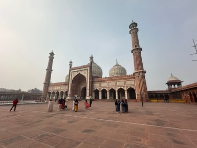 Die Jama Masjid in Delhi, umgeben von Besuchern, zeigt beeindruckende Architektur mit hohen Minaretten und Kuppeln.