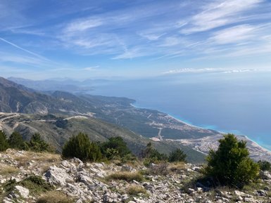 Ein atemberaubender Blick auf die Küste von Llogara Nationalpark, mit Bergen und dem glitzernden blauen Wasser des Meeres.
