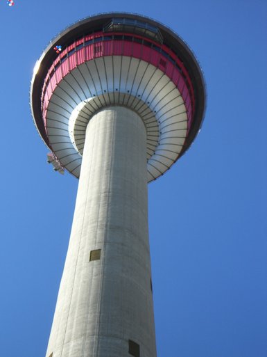 Der Calgary Tower ragt majestätisch in den blauen Himmel, mit einer markanten rot-weißen Aussichtsplattform oben.