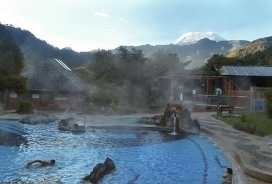Ein entspannendes Thermalbad in Papallacta, umgeben von grünen Bergen und dampfendem Wasser, das eine friedliche Atmosphäre schafft.