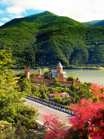 Eine malerische Landschaft mit einem historischen Kloster, umgeben von üppigen grünen Bergen und einem ruhigen See.