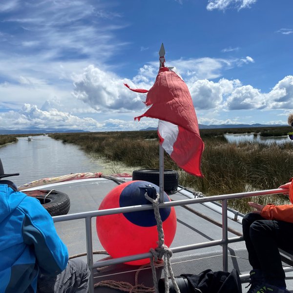Zwei Kinder sitzen auf einem Boot, während sie die ruhige Wasserlandschaft des Titicaca-Sees genießen.