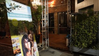 Ein Werbeschild für Familienreisen zeigt eine Mutter mit ihrer Tochter, umgeben von Tieren in einer grünen Landschaft.