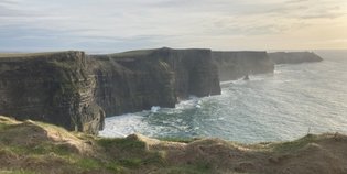Die Klippen von Moher erheben sich majestätisch über dem tosenden Atlantik, umgeben von sanften grünen Hügeln.