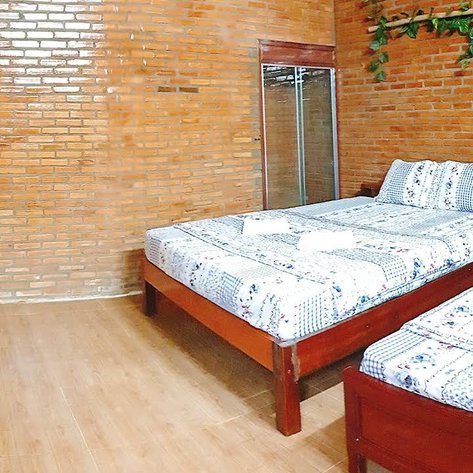 Ein gemütliches Zimmer mit zwei Betten, Holzfußboden und Ziegelwänden, ideal für einen Aufenthalt in der Natur.