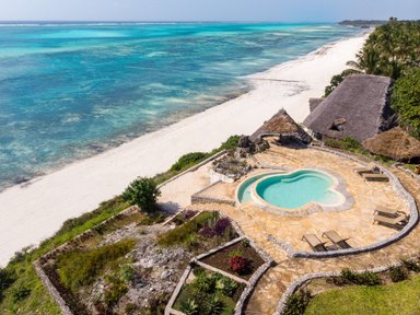 Ein herzförmiger Pool liegt inmitten von üppigen Gärten, mit Blick auf den weißen Sandstrand und das türkisfarbene Wasser.