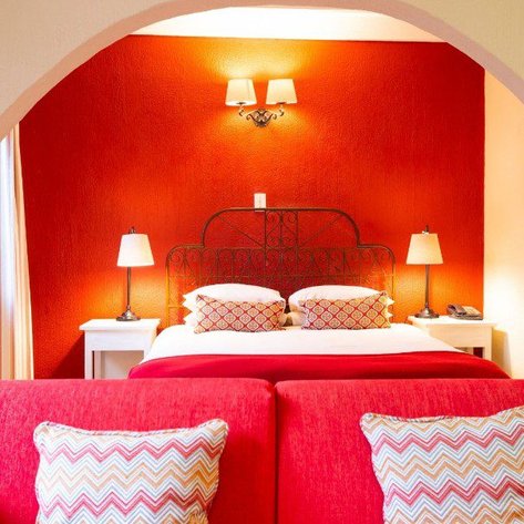 Ein gemütliches Schlafzimmer mit einem roten Akzentwand, einem Doppelbett und stilvollen Nachttischlampen.