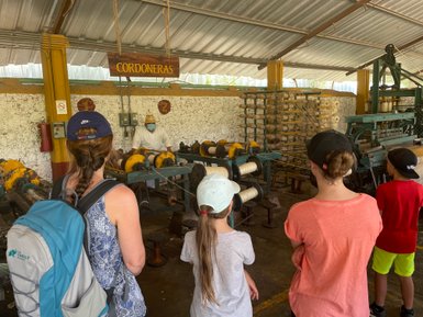 Kinder verfolgen gespannt, wie Sisalfasern auf der Hacienda Sotuta de Peón mit historischen Geräten verarbeitet werden – Mexiko Reise mit Kindern