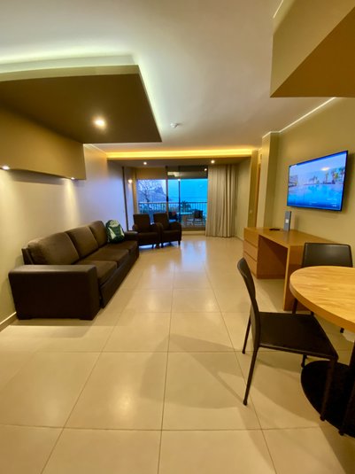 Ein modernes Wohnzimmer mit einem bequemen Sofa, einem Tisch und einem Fernseher, der an der Wand montiert ist.