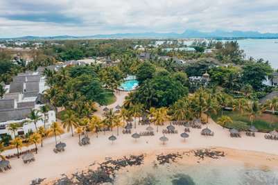 Ein Blick auf den Mauritius Canonnier Beachcomber Golf Resort mit üppigen Palmen und einem einladenden Pool in der Mitte.