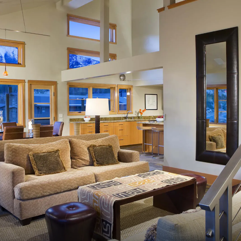 Ein modernes Wohnzimmer mit großen Fenstern, das einen Blick auf die Berge bietet, und stilvollen Möbeln für Komfort.