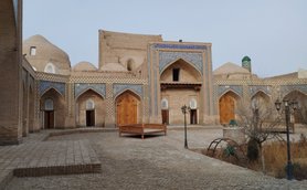 Eine historische Architektur mit kunstvollen Fliesen und Holztüren, umgeben von einem gepflasterten Innenhof.