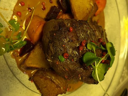 Ein saftiges Elchsteak liegt auf einem Teller, umgeben von buntem Gemüse und einer cremigen Sauce.