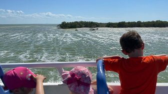 Kinder sitzen gespannt im Boot auf ruhigem Wasser – Mexiko Familienreise