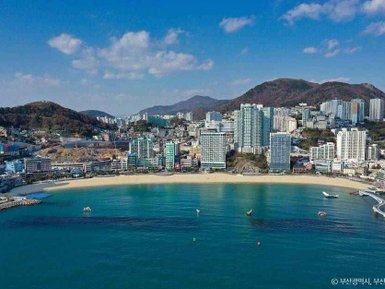 Ein atemberaubender Blick auf den Strand von Songdo, umgeben von modernen Hochhäusern und sanften Hügeln im Hintergrund.