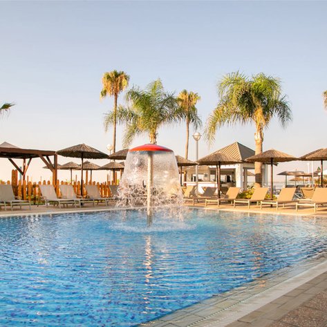 Ein einladender Pool mit sprudelndem Wasser, umgeben von Liegen und Palmen, ideal für entspannende Tage am Atlantik.