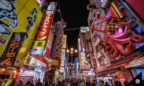 Bunte Neonlichter erhellen eine belebte Straße in Osaka, gesäumt von Geschäften und einem riesigen, pinken Oktopus.