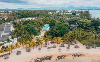 Ein Blick auf den Mauritius Canonnier Beachcomber Golf Resort mit üppigen Palmen und einem einladenden Pool in der Mitte.