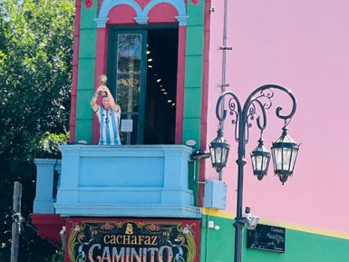 Ein bunter Balkon in Buenos Aires zeigt eine Statue eines Fußballspielers, der einen Pokal triumphierend in die Höhe hält.