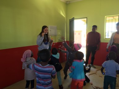 Eine Frau macht Seifenblasen für Kinder - Namibia mit Jugendlichen