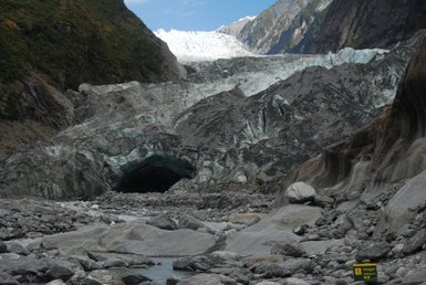 Ein majestätischer Gletscher erstreckt sich über die Berge, umgeben von steilen Felsen und glatten Gesteinsformationen.