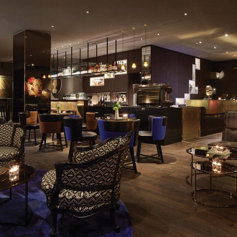 Ein eleganter Lounge-Bereich mit stilvollen Möbeln, sanfter Beleuchtung und einer Bar im Hintergrund, die Getränke anbietet.