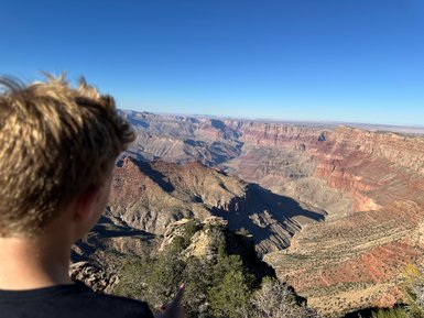 Ein Junge steht am Rand des Grand Canyon und blickt auf die beeindruckende Landschaft mit roten Felsen und tiefen Schluchten.