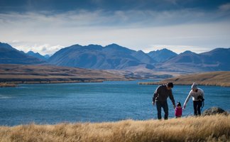 Eine Familie genießt einen sonnigen Tag am Wasser, während die Berge im Hintergrund majestätisch aufragen.
