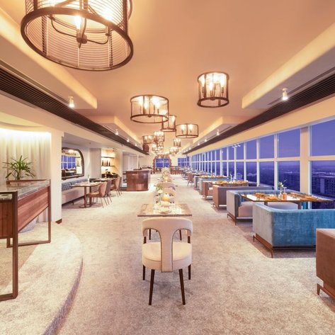 Ein elegantes Restaurant mit modernen Möbeln und großen Fenstern, die einen Blick auf die Stadt bieten.