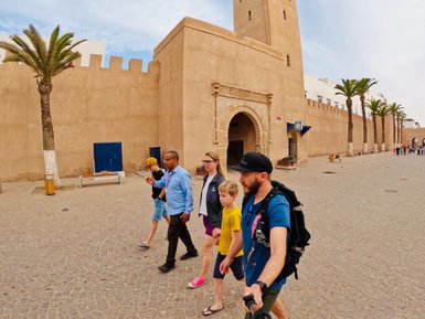 Familie spaziert durch die Straßen von Essaouira, umgeben von braunen Gebäuden – Marokko mit Kindern