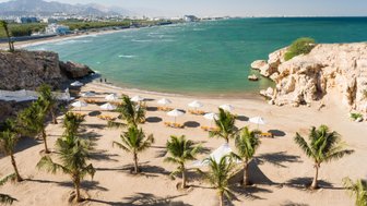 Strand des Crowne Plaza Muscat mit Liegestühlen und Sonnenschirmen – Familienurlaub in Muscat