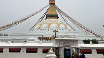 Der Bodhnath Stupa in Nepal, umgeben von bunten Gebetsfahnen, zieht zahlreiche Besucher an, die die heilige Stätte erkunden.
