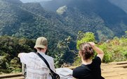 Zwei Jugendliche sitzen auf einem Aussichtspunkt und genießen die atemberaubende Aussicht auf die grünen Berge Sri Lankas.