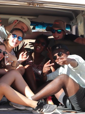 Eine Reisegruppe sitzt beisammen im offenen Kofferraum eines Jeeps - Namibia Rundreise mit Kindern
