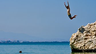 Kind springt ins Wasser am Strand vom Crowne Plaza Muscat – Oman Reise mit Kindern