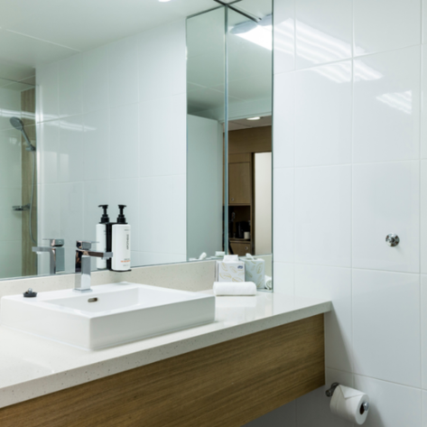 Ein modernes Badezimmer mit einem eleganten Waschbecken, weißen Fliesen und Holzelementen, das ein Gefühl von Sauberkeit vermittelt.