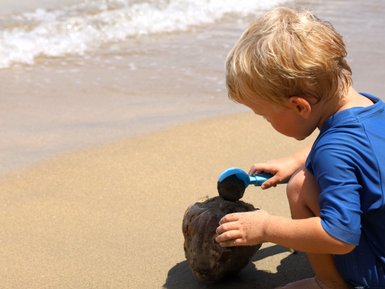 Kleines Kind spielt fröhlich im Sand am Strand – Costa Rica Familienreise
