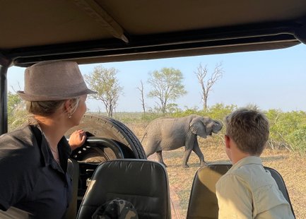 Mutter und Sohn sitzen im Safari-Jeep und beobachten gemeinsam Tiere in der Savanne – Südafrika Familienreise