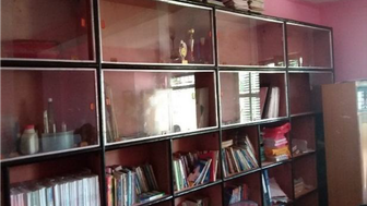 Ein Bücherregal mit bunten Büchern und Ordnern, umgeben von einer pinken Wand, strahlt eine einladende Atmosphäre aus.