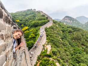 Teenager grüßt von der Großen Mauer mit weitem Blick auf die Landschaft Chinas – China Reise mit Kindern