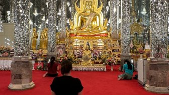 Frau blickt kniend auf die golden Statue im Wat Chantharam Tempel in Uthai Thani - Thailand Familienreise