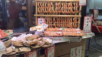 Ein Marktstand in Kyoto bietet eine Vielzahl von gegrillten Garnelen und Meeresfrüchten, umgeben von warmem Licht.