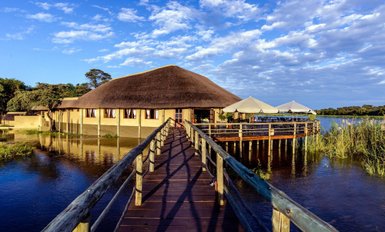 Lodge mit Reetdach, direkt am Wasser gelegen, mit Steg und Terrasse über dem Fluss - Namibia Familienreise