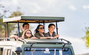 Familie erkundet mit Guide die Tierwelt in einem Safarijeep – Tansania mit Kindern