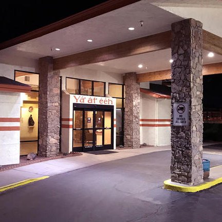 Das NavajoLand Hotel präsentiert sich mit einem einladenden Eingangsbereich, beleuchtet von warmem Licht in der Nacht.