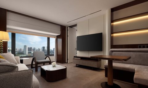 Ein elegantes Hotelzimmer mit modernem Design, das eine gemütliche Sitzecke und einen Blick auf die Stadt bietet.