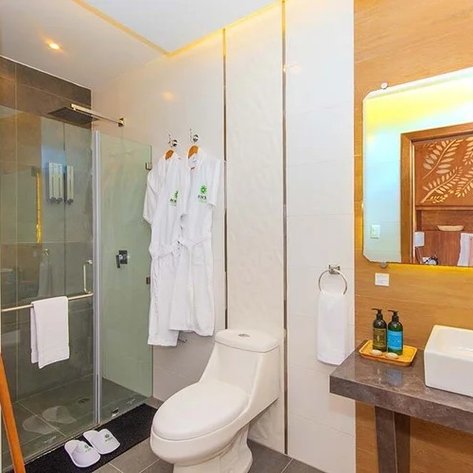 Ein modernes Badezimmer mit einer Glasdusche, weißen Handtüchern und Bademänteln, die an einem Ständer hängen.